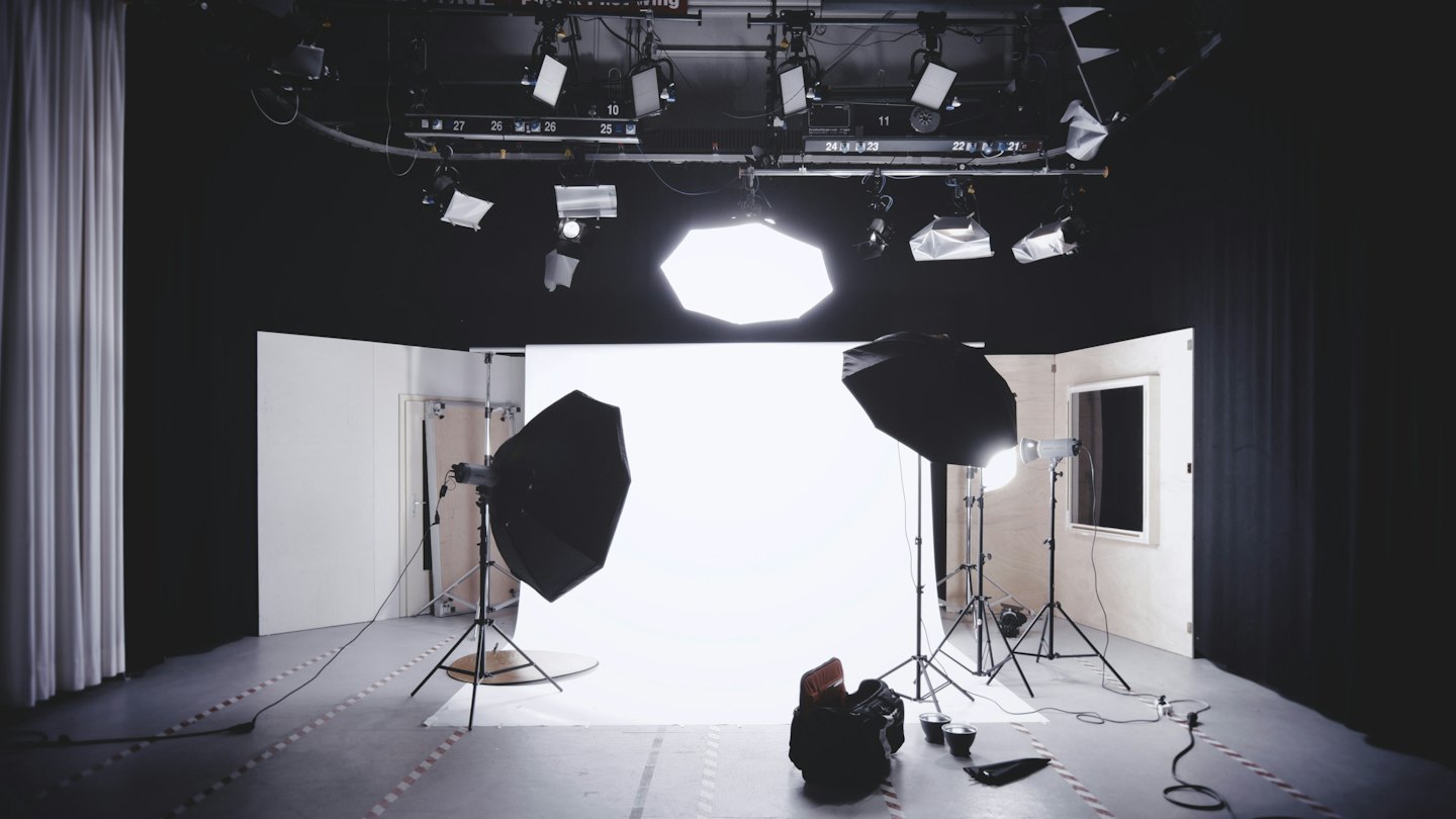 Jasne studio fotograficzne z białym tłem bez szwów i sprzętem oświetleniowym.
